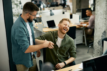 Cheerful businessmen laughing and having fun while working in office.