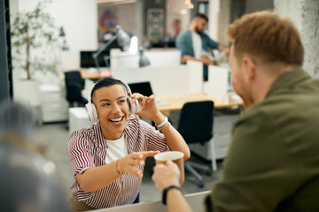 Happy black businesswoman getting cup of coffee from her colleague while working in office.