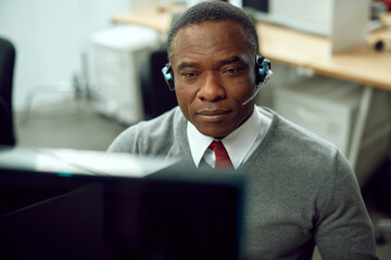 African American call center agent working on computer in office.