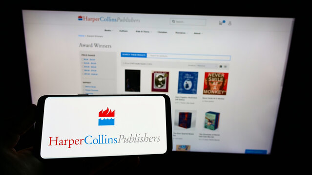Stuttgart, Germany - 02-05-2022: Person holding mobile phone with logo of American company HarperCollins Publishers LLC on screen in front of web page. Focus on phone display.