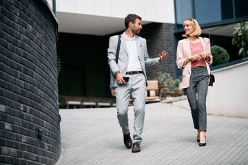 Smiling businesswoman and her colleague talk while talking on the street.