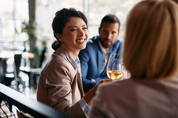 Cheerful businesswoman has fun while toasting with her colleagues in restaurant.