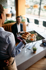 Close up of waitress serving food to a businessman in cafe.