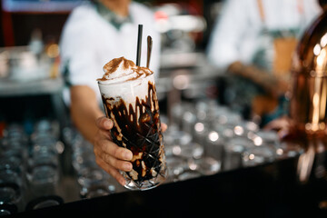 Close up of waitress serving serving chocolate mocha in tall glass.