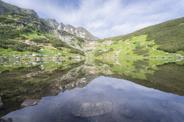 Fototapeta na wymiar Still crystal clear alpine tarn reflecting its surroundings like a mirror, Slovakia, Europe