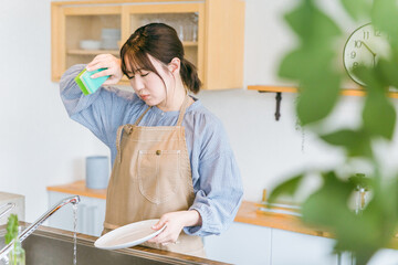 洗い物をする日本人女性（疲労）
