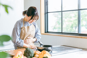 料理中に体調不良になる女性（お腹）
