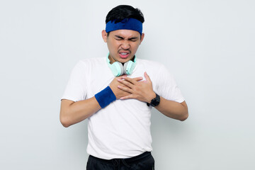 young Asian sportman in blue headband and white t-shirt with headphones, presses a hand to chests...