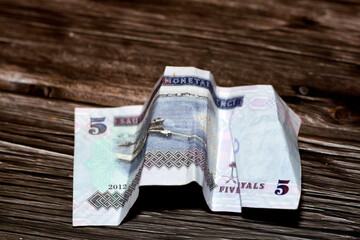 Crumpled Saudi Arabia money of 5 SAR five riyals isolated on wooden background, wrinkled 5 Saudi...