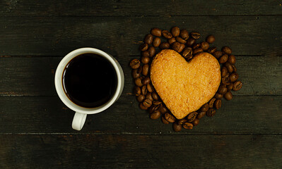 A cup of coffee and love cookie with coffee beans on wooden surface,top view.Valentine day holiday.