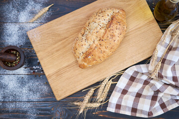 Fresh bread loaf on wooden cutting board at kitchen table