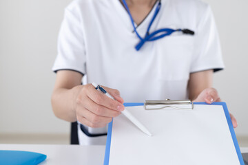 病院の受付で外来診療申込書の書き方を説明する女性