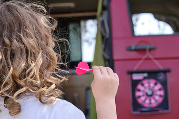 Rear view of a child playing darts on vacation.