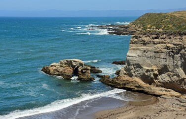 The rugged, rocky coastline and crashing waves of the california coast south of morro bay in...