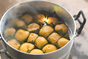 Yellow toddy palm cake (Kanom Tarn) thailand food on banana leaf in steaming pot close-up.