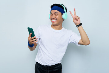 smiling young Asian sportman in blue headband and sportswear white t-shirt while listening music...