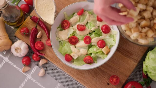 cooking Caesar salad inside deep cooking bowl - adding croutons