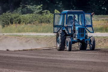 Work of a tractor on a hippodrome. Agricultural machinery. Rural transport. Level the ground on the track. Preparation of the route for horses at the racetrack.