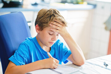 Young boy doing his homework at home. School kid learning.