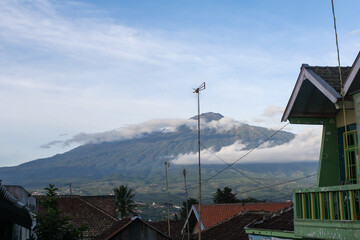 Scenery of Mount Arjuno Welirang at sunset from village with clouds in blue sky background in Batu, Indonesia.