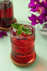 Freshly brewed iced red fruit tea on green table