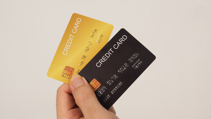 Hand is holding two credit card in black and gold color isolated on white background.