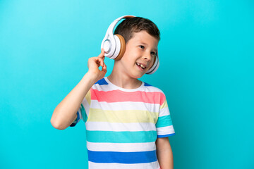 Little boy isolated on blue background listening music and singing