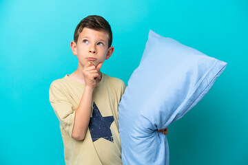 Little boy in pajamas isolated on blue background and looking up