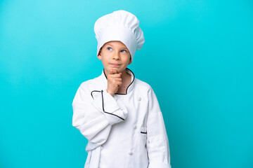 Little chef boy isolated on blue background and looking up