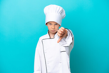 Little chef boy isolated on blue background showing thumb down with negative expression