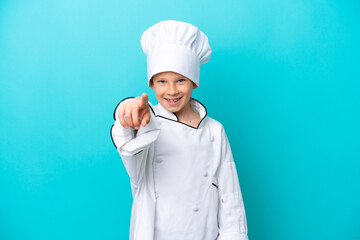 Little chef boy isolated on blue background pointing front with happy expression