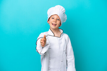Little chef boy isolated on blue background shaking hands for closing a good deal