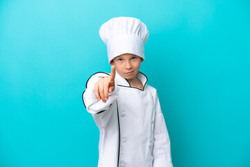 Little chef boy isolated on blue background showing and lifting a finger