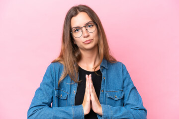 Young caucasian woman isolated on pink background keeps palm together. Person asks for something