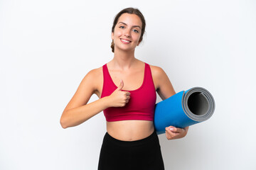 Young sport caucasian woman going to yoga classes while holding a mat isolated on white background giving a thumbs up gesture