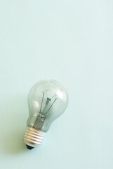 Traditional style glass light bulb with burnt tungsten on blue background.