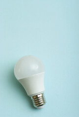 White economy light bulb on blue background with free copy paste space for text.