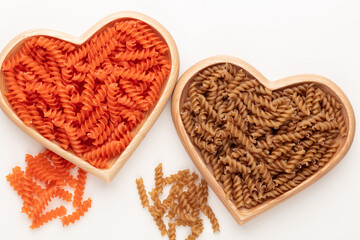 Red lentil fusilli pasta in a heart shaped wood bowl.