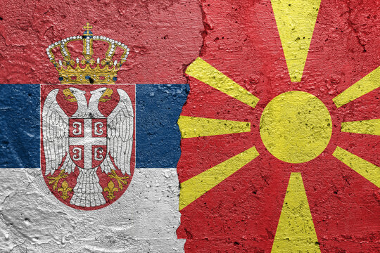 Serbia and North Macedonia - Cracked concrete wall painted with a Serbian flag on the left and a Macedonian flag on the right stock photo