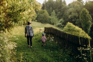 Fototapeta premium Summer trip with children to the mountains. Evening walk of a mother with a child in an alpine village in summer.