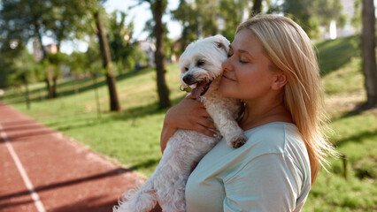 Young smiling caucasian girl hugging Maltese dog