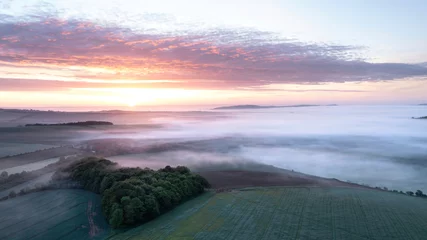 Wall murals Morning with fog Majestic drone landscape image of sea of fog rolling across South Downs English countryside during Spring sunrise