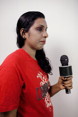 Young  woman holding microphone doing television speech outdoors