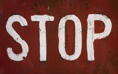 word stop written with paint on red rusted metallic plate