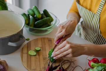 Unrecognizable female hands chopping aromatic cucumbers for mixed vitamin salad. Homemade healthy food. Detox and diet