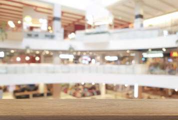 empty wooden table in front of blurred background of shopping mall atrium can be used for display...