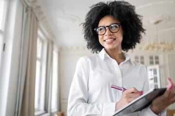 Manager a woman with glasses uses a tablet makes notes on work , office workplace coworking space