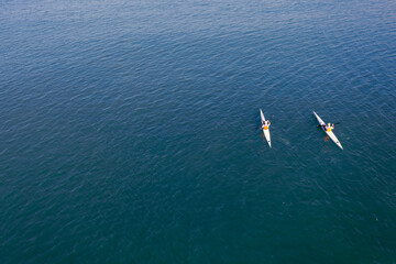Obraz premium Aerial view of two white kayaks, rowing in the sea with turquoise water