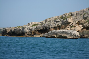 Foto di una scogliera di pietra bianca, con grande masso simile a un isolotto al centro del mare