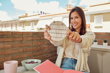 Beautiful and young woman relaxing on the terrace of her house reading and eating cherries.
